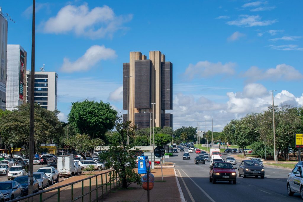 Governo reduz projeção de crescimento do PIB para 2% em 2026 Vista urbana de Brasília com o prédio do Banco Central do Brasil sob um céu colorido.