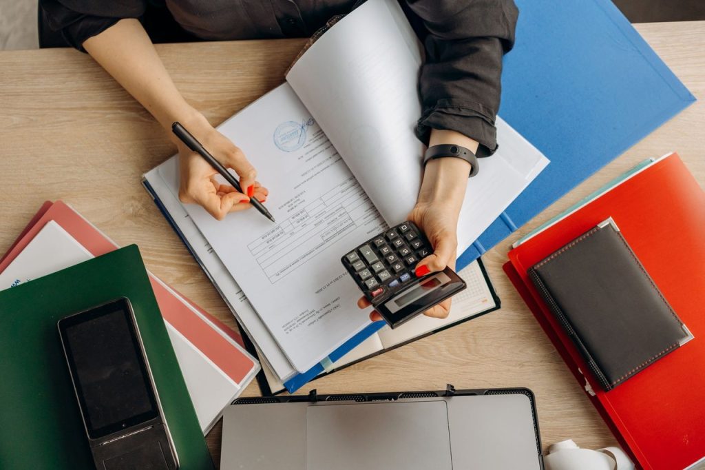 Profissional analisa documentos financeiros com uma calculadora sobre a mesa.
