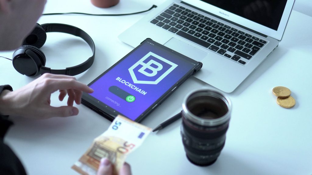 U.S. Bank testa stablecoin própria em pagamento internacional entre América do Norte e Europa Tablet exibindo uma transação de moeda digital ao lado de um laptop e cédulas de euro.